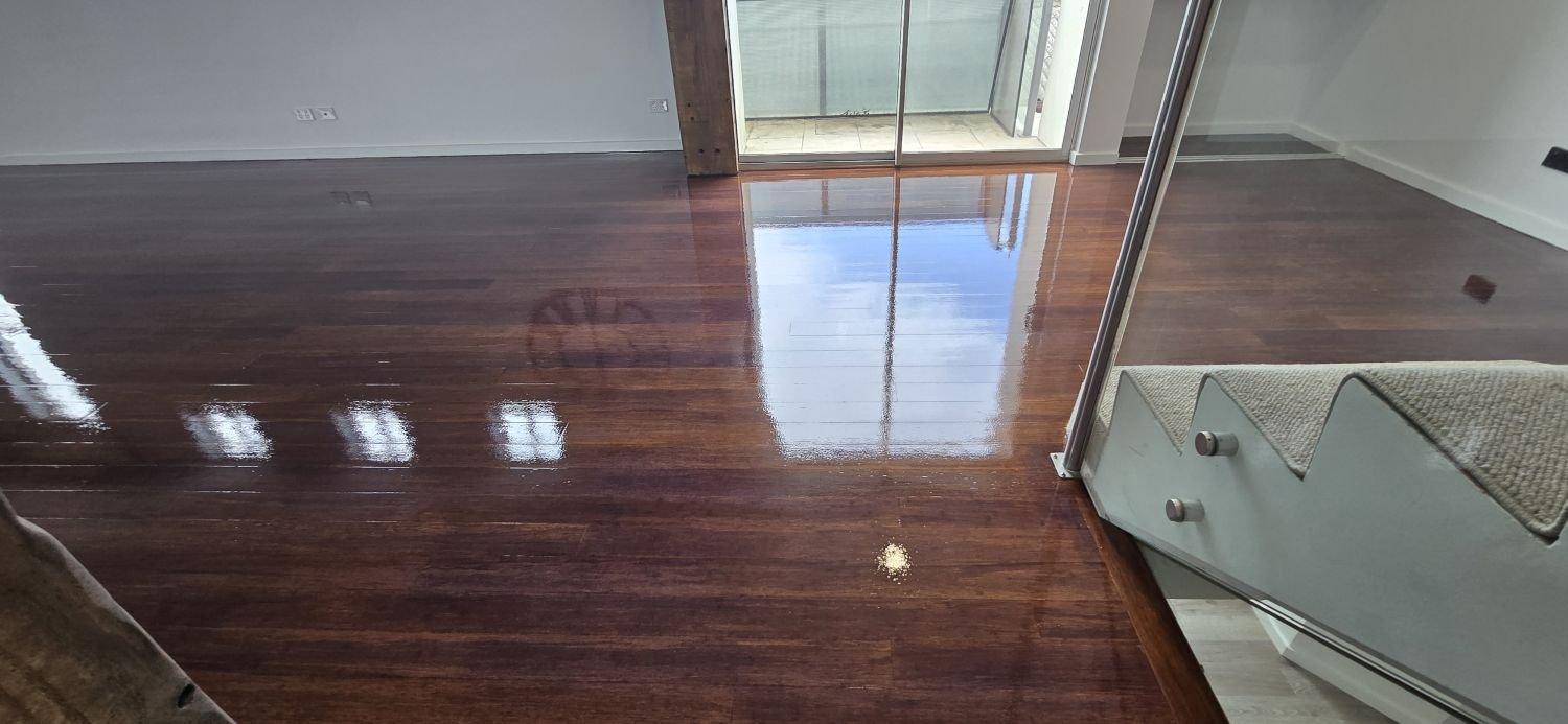 Reflected window light on a freshly polished dark hardwood floor.