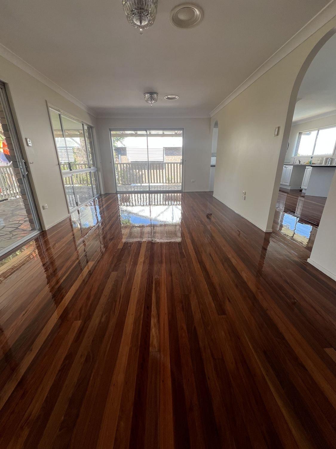 Living room with polished dark wood floors, sliding glass doors and windows.