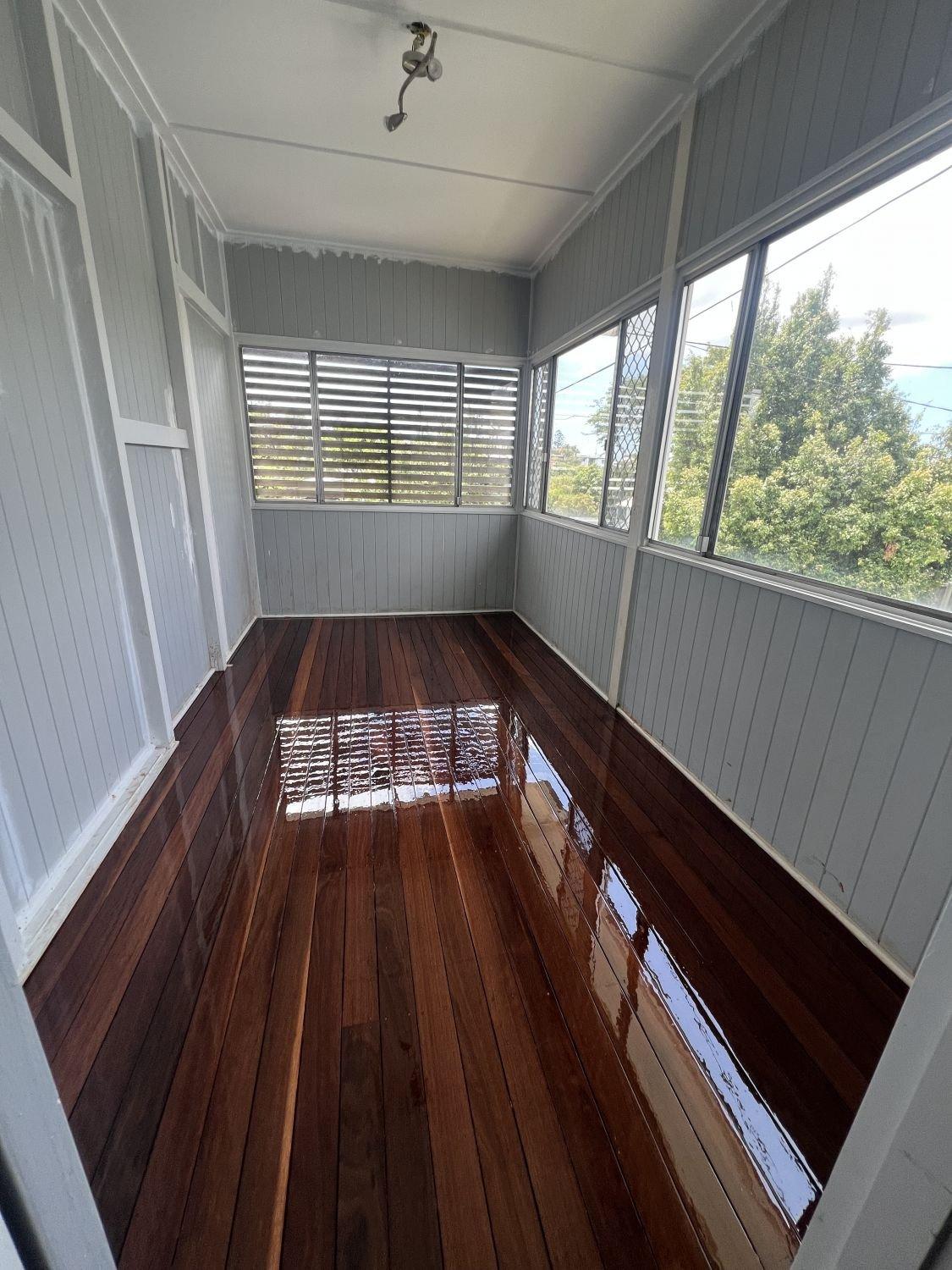 Enclosed porch with freshly polished floorboards and windows on three sides.