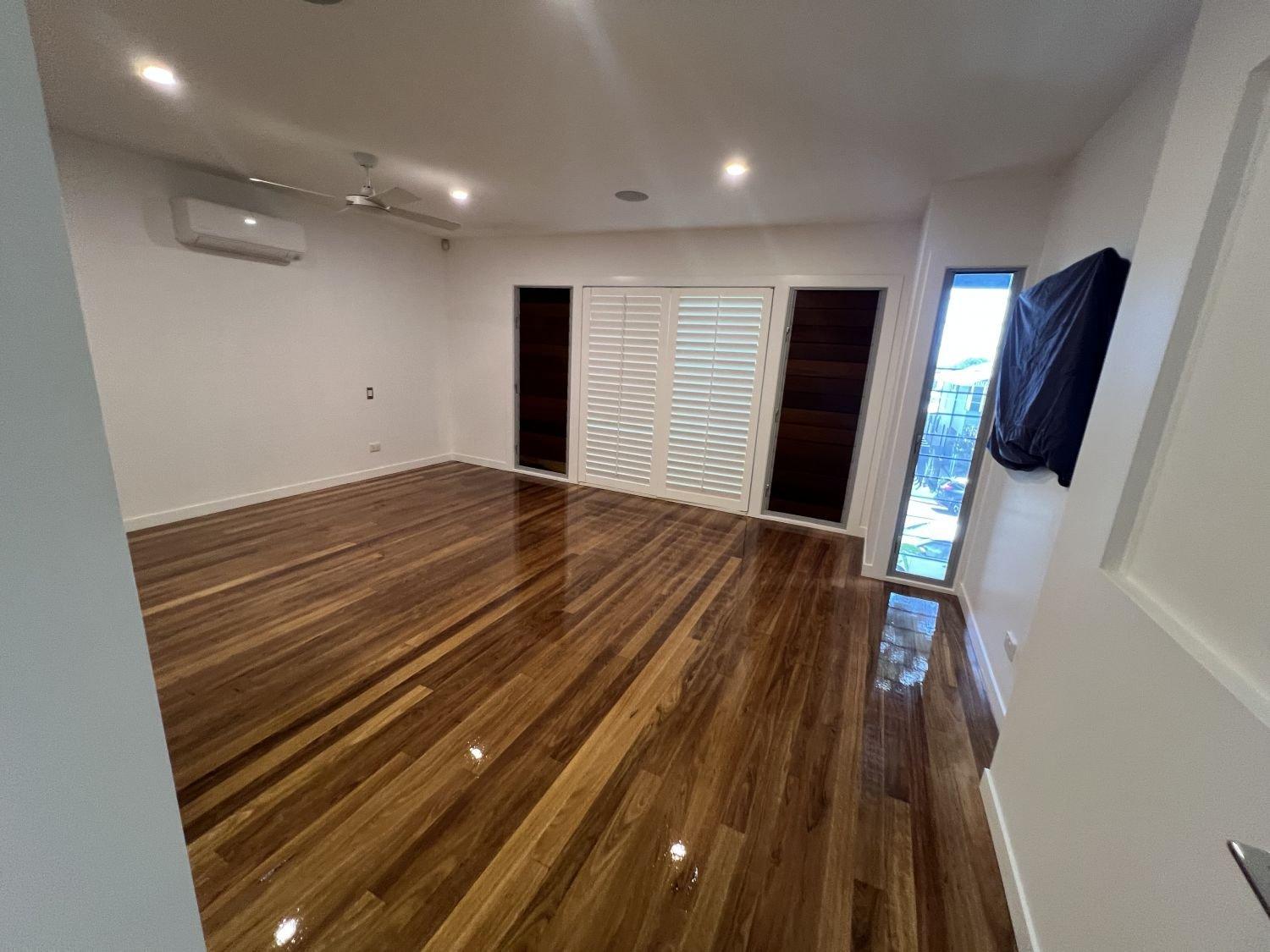 Room with hardwood floors, white walls, shuttered sliding doors and a window.