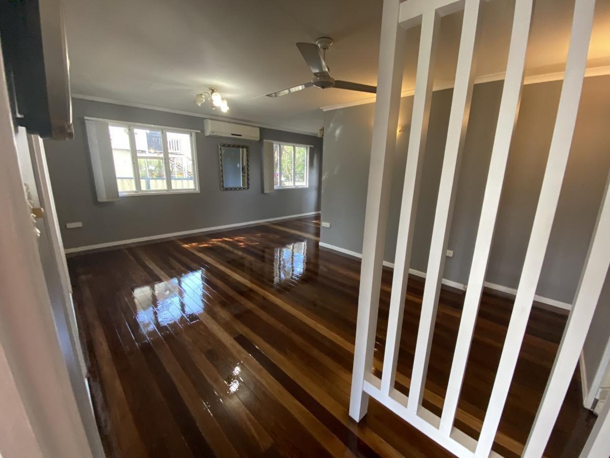 Living room with hardwood floors, grey walls, two windows and a ceiling fan.