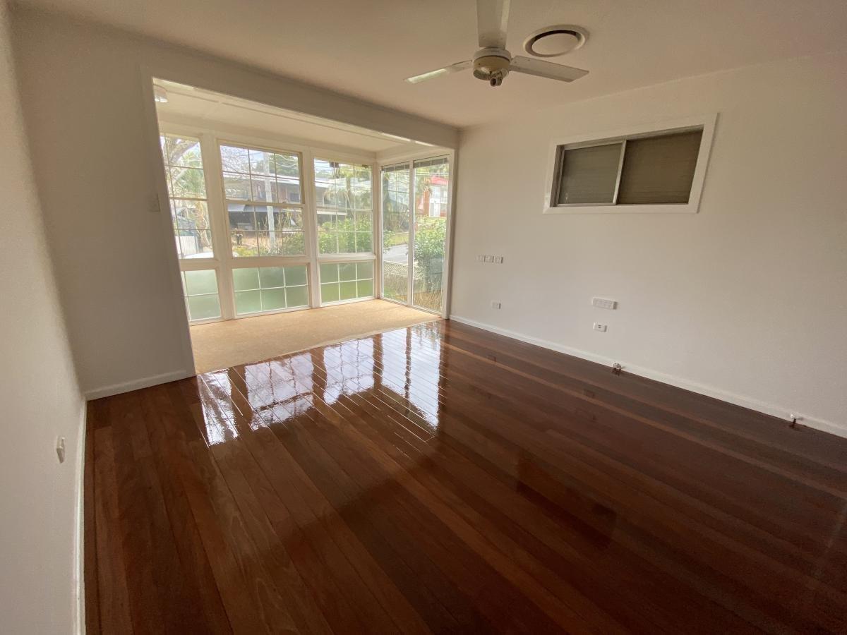 Room with polished wooden floor, white walls, ceiling fan and glass-block window.