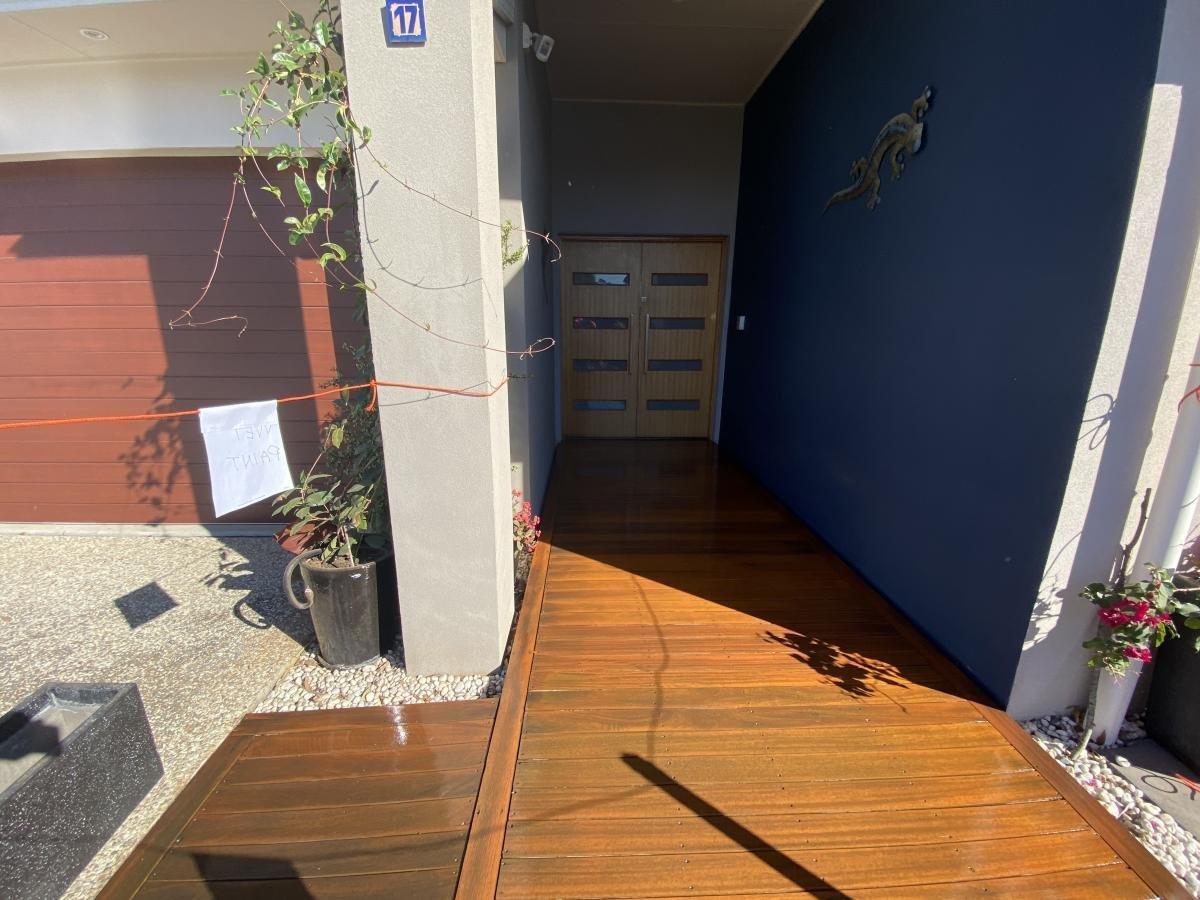 Modern house entrance with a wooden deck, dark blue wall and double wooden doors.