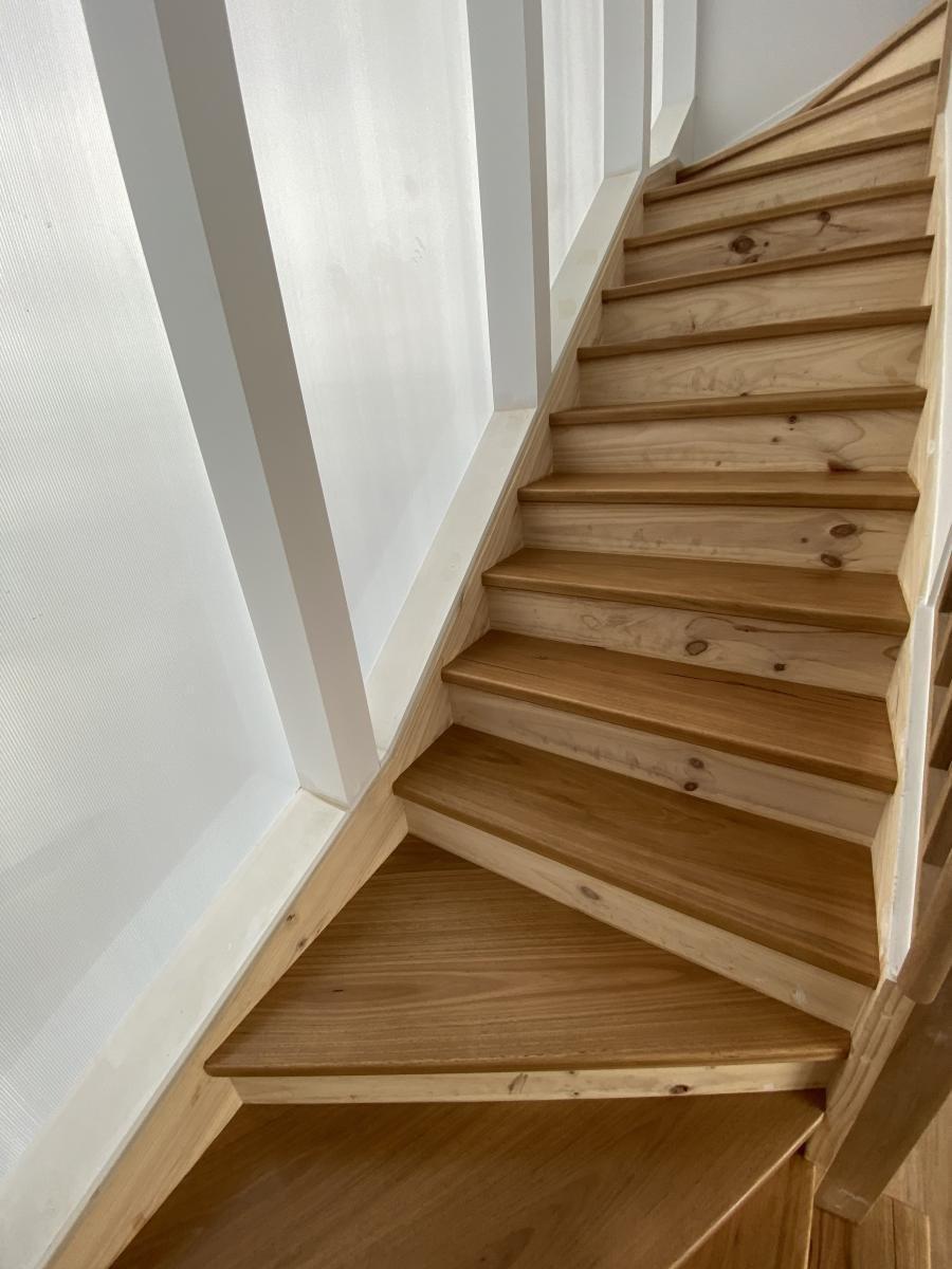 Turning wooden staircase set against clean white walls.