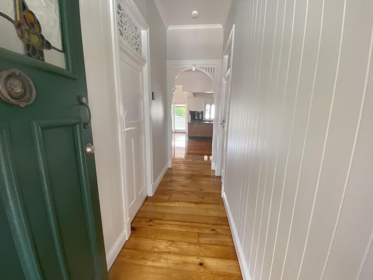 Hallway with wood floors, white walls and an arched entry.