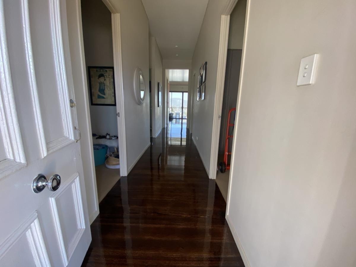 Hallway with polished wooden floors and artwork, leading to a balcony.
