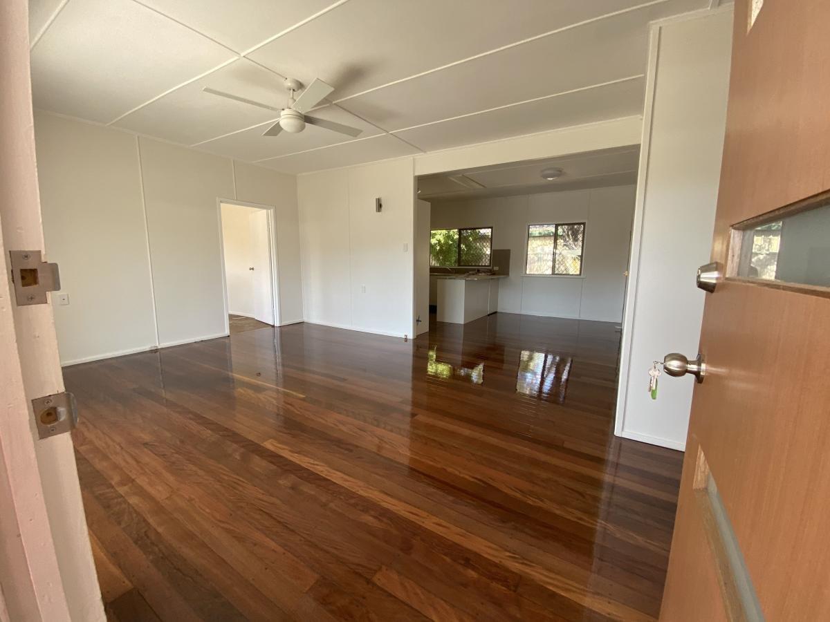Room with polished hardwood floors, white walls, ceiling fan and an open doorway.